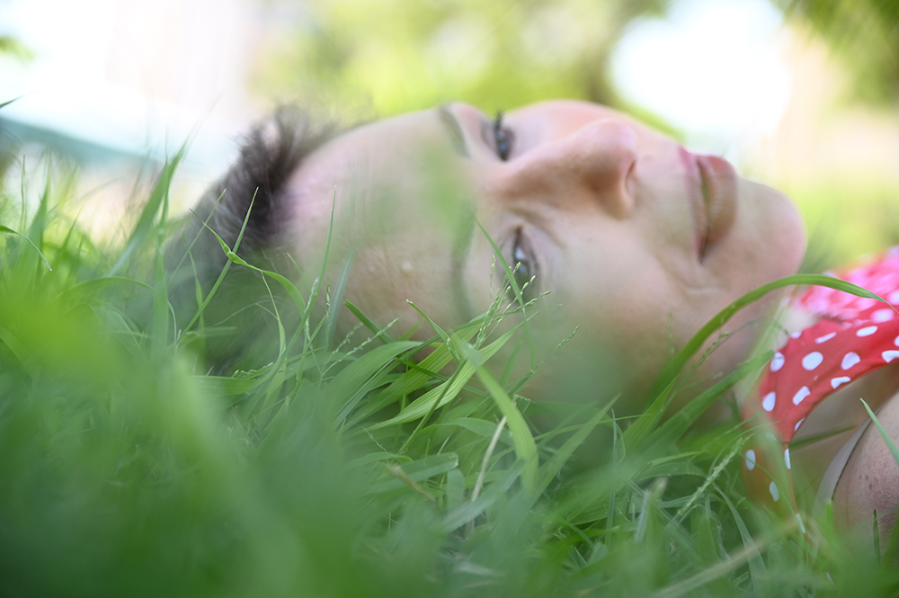 צילום לאישה ששכובת על דשא ירוק בטבע