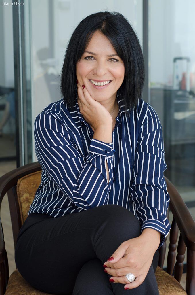 צילום תדמית במשרד למנהלת, אישה בחולצת פסים יושבת בנינוחות בסביבת העבודה ומשדרת ביטחון